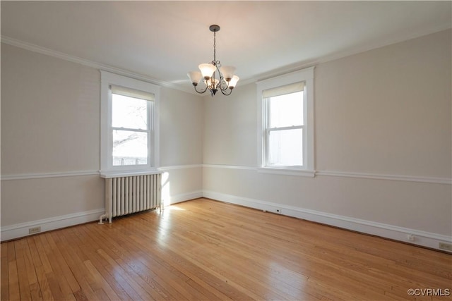 empty room with a wealth of natural light, a chandelier, light hardwood / wood-style floors, and radiator heating unit