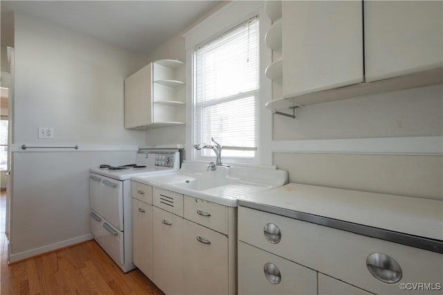 kitchen with electric range, light wood-type flooring, white cabinets, and sink