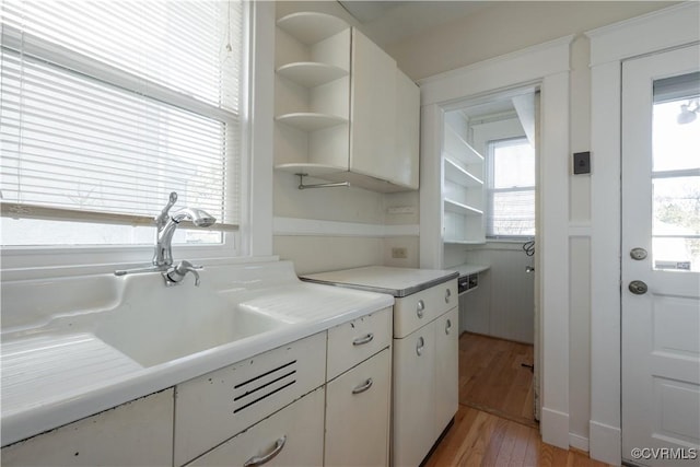 kitchen featuring sink, white cabinetry, and light wood-type flooring