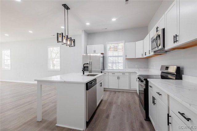 kitchen featuring light wood-style flooring, plenty of natural light, appliances with stainless steel finishes, and a center island with sink