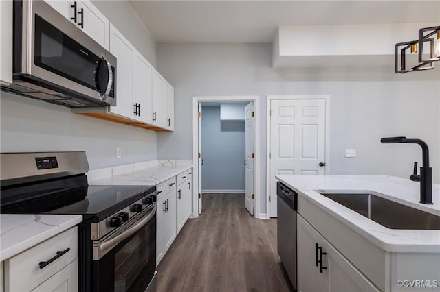 kitchen featuring a sink, light stone counters, dark wood finished floors, appliances with stainless steel finishes, and white cabinets