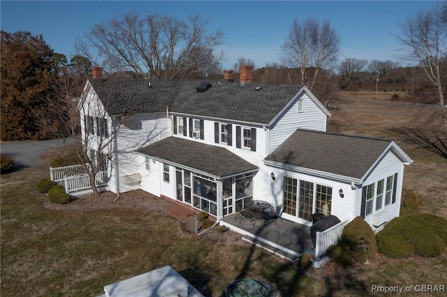 rear view of house featuring a lawn, a sunroom, and a patio