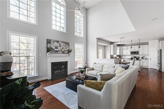 living room featuring dark wood-type flooring, a wealth of natural light, and a high ceiling