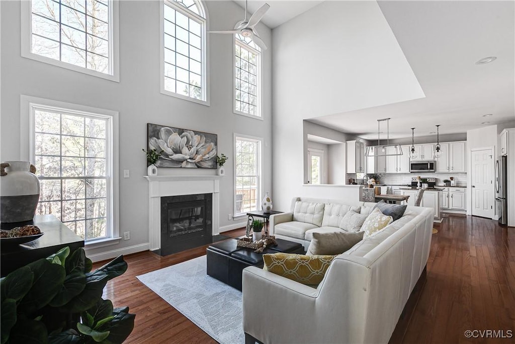 living room with a high ceiling, dark wood-type flooring, and a wealth of natural light