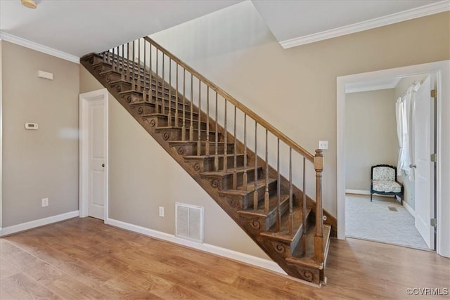 stairway featuring ornamental molding and wood-type flooring