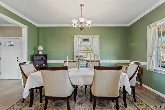 dining area with a notable chandelier, wood-type flooring, and ornamental molding