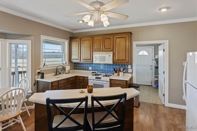 kitchen featuring wood-type flooring, sink, backsplash, ceiling fan, and white appliances