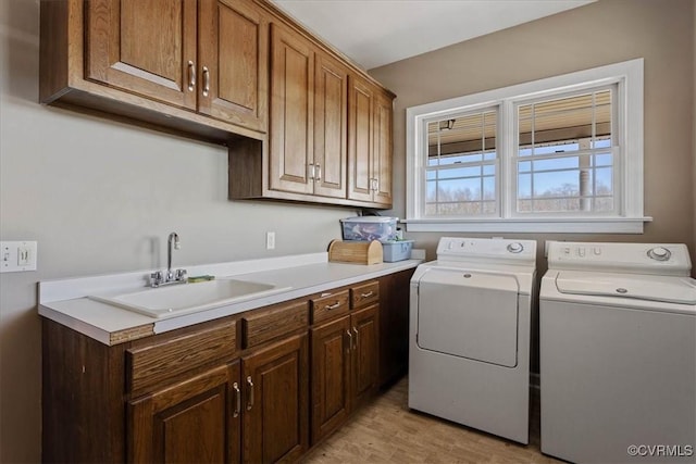 laundry area featuring cabinets, sink, independent washer and dryer, and light wood-type flooring