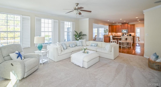 living room with ceiling fan, light colored carpet, and crown molding