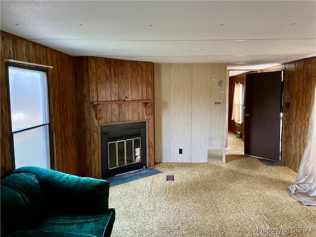 living room with a large fireplace, carpet floors, and wood walls