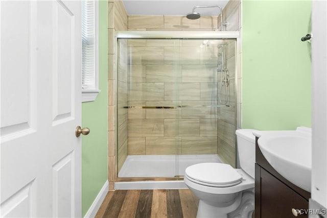 bathroom featuring wood-type flooring, toilet, an enclosed shower, and vanity