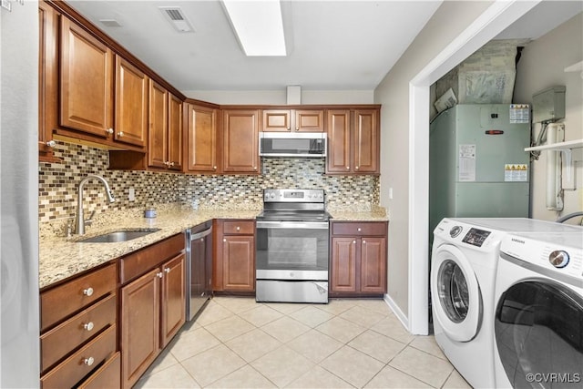 kitchen with sink, tasteful backsplash, washer and dryer, stainless steel appliances, and light stone countertops