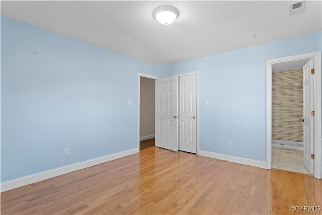 unfurnished bedroom featuring light hardwood / wood-style floors and ensuite bathroom