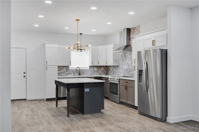 kitchen featuring pendant lighting, a center island, stainless steel appliances, wall chimney range hood, and white cabinets