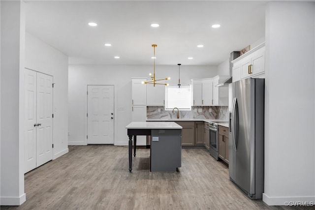 kitchen with stainless steel appliances, a kitchen island, sink, decorative light fixtures, and backsplash