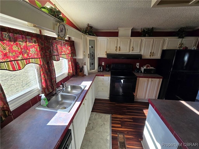 kitchen with a textured ceiling, white cabinets, black appliances, dark hardwood / wood-style flooring, and sink