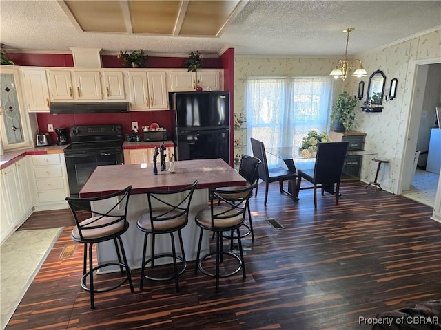 kitchen featuring white cabinets, black appliances, decorative light fixtures, an inviting chandelier, and crown molding