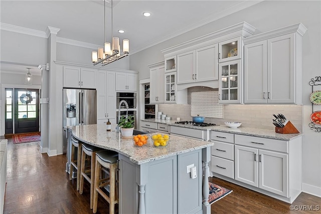 kitchen with backsplash, stainless steel appliances, an island with sink, and white cabinets