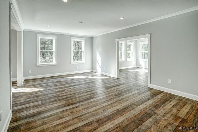 empty room with ornamental molding, dark hardwood / wood-style flooring, and a healthy amount of sunlight