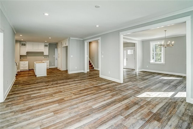 unfurnished living room featuring a notable chandelier, light hardwood / wood-style floors, and crown molding