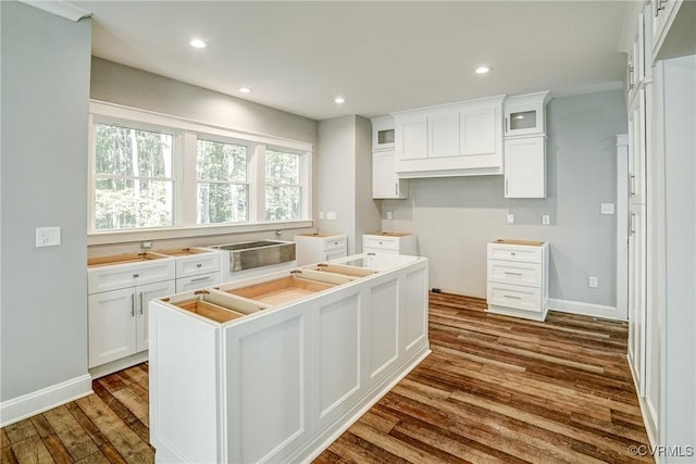 kitchen featuring white cabinets, a center island, crown molding, and hardwood / wood-style flooring