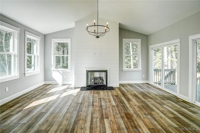 unfurnished living room with an inviting chandelier, vaulted ceiling, a fireplace, and hardwood / wood-style flooring