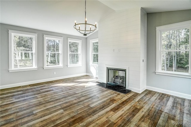 unfurnished living room featuring a notable chandelier, vaulted ceiling, a fireplace, and hardwood / wood-style flooring