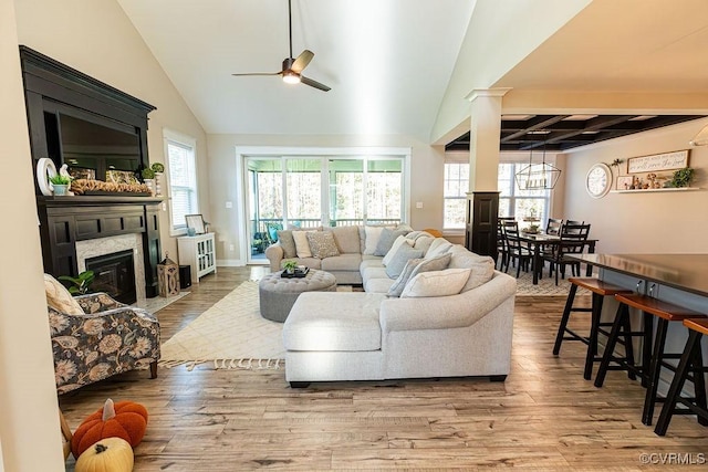 living room with beamed ceiling, a high end fireplace, decorative columns, hardwood / wood-style flooring, and ceiling fan