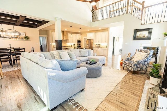 living room with coffered ceiling, light wood-type flooring, beam ceiling, and a high ceiling