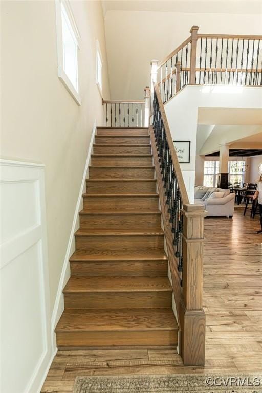 stairway with hardwood / wood-style flooring and a towering ceiling