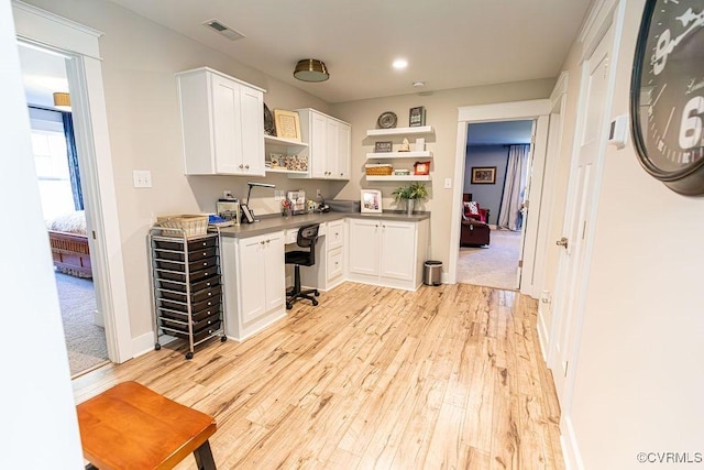 bar featuring white cabinets, built in desk, and light hardwood / wood-style floors