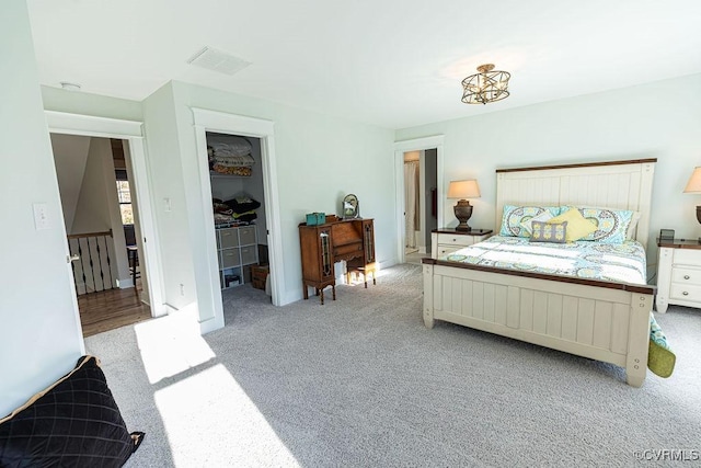 bedroom with light carpet, a closet, and a walk in closet