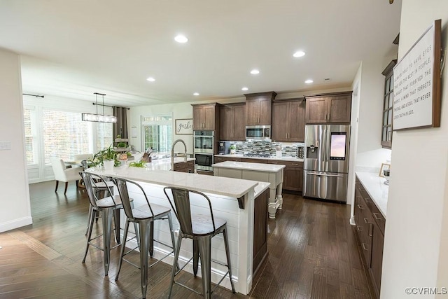 kitchen featuring a large island, a kitchen breakfast bar, pendant lighting, stainless steel appliances, and dark hardwood / wood-style floors