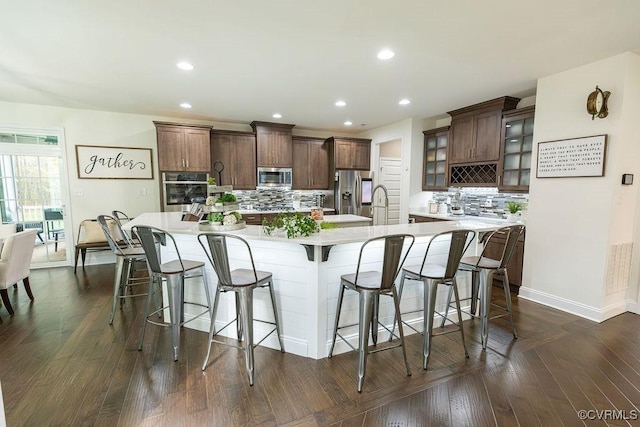 kitchen featuring a kitchen breakfast bar, a spacious island, appliances with stainless steel finishes, dark hardwood / wood-style floors, and decorative backsplash