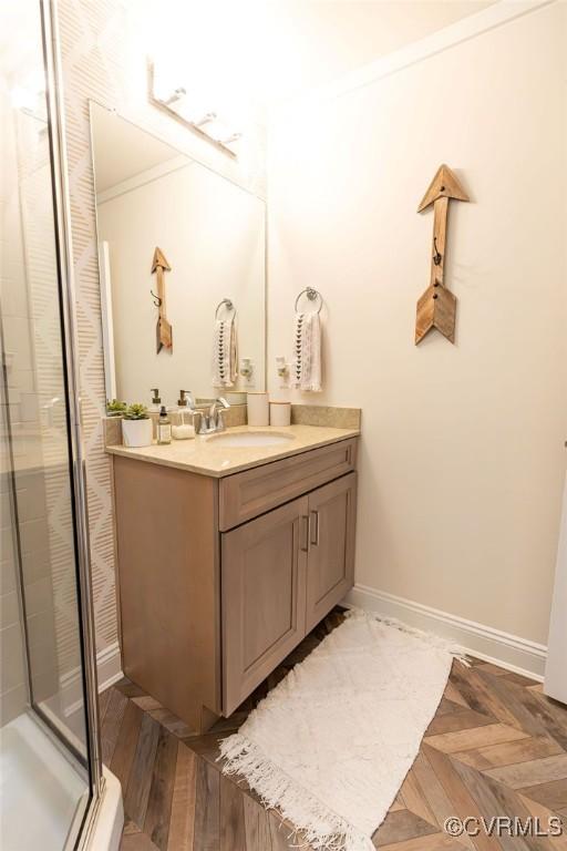 bathroom featuring vanity, a shower with shower door, parquet floors, and ornamental molding