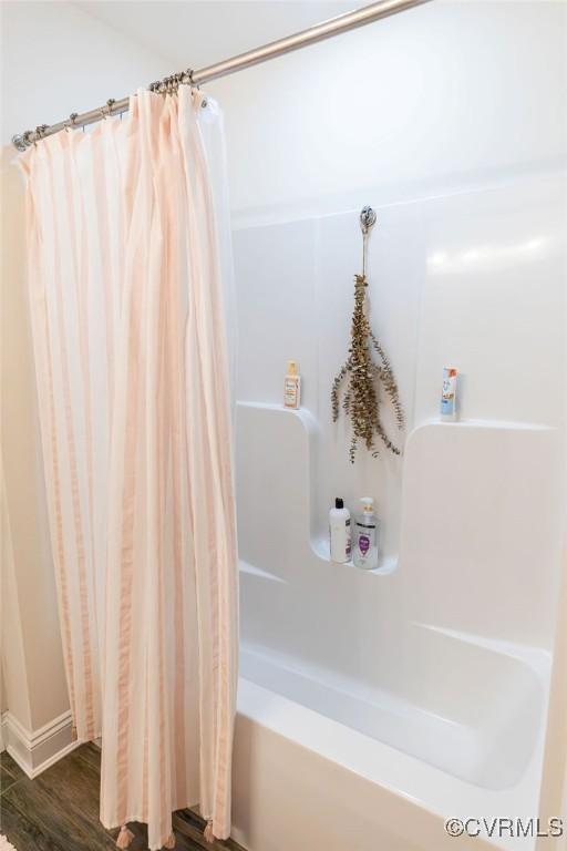 bathroom with hardwood / wood-style floors and shower / bath combo with shower curtain