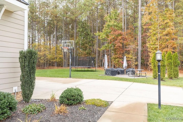 view of basketball court with a trampoline and a lawn