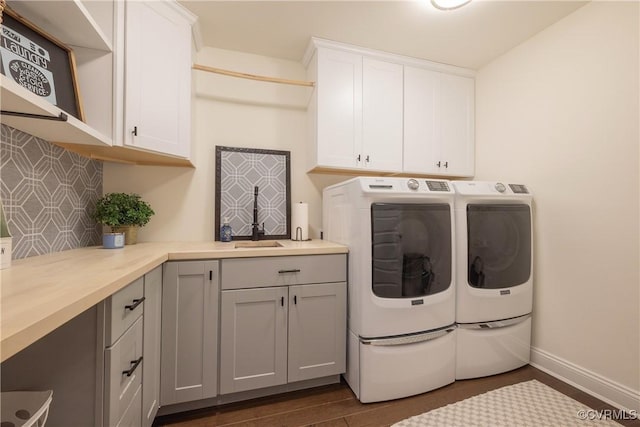 laundry area featuring dark wood-type flooring, cabinets, sink, and washing machine and dryer