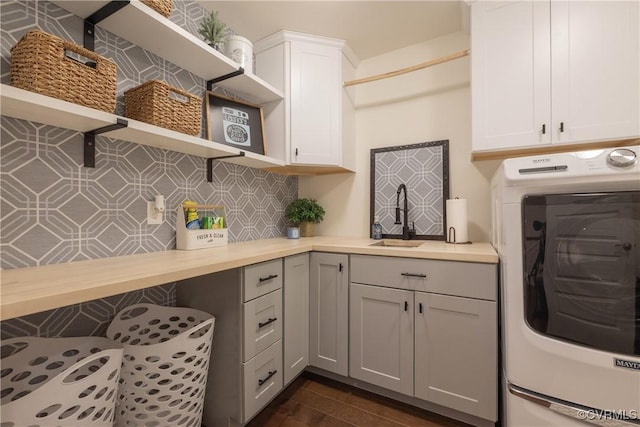 laundry room with washer / clothes dryer, sink, dark wood-type flooring, and cabinets