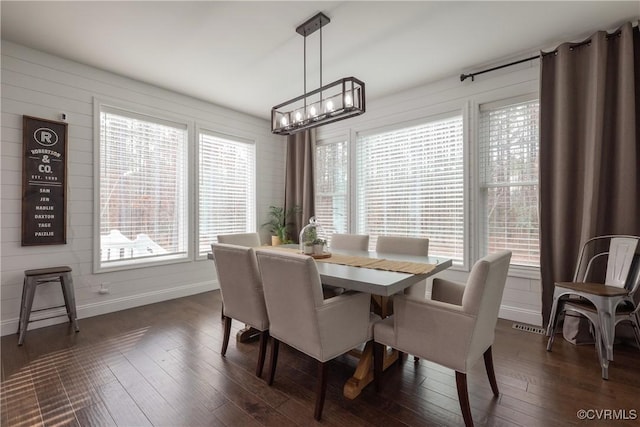 dining room featuring dark hardwood / wood-style flooring, a healthy amount of sunlight, and an inviting chandelier