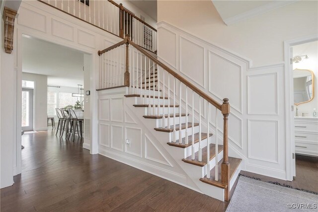 stairway with crown molding and wood-type flooring