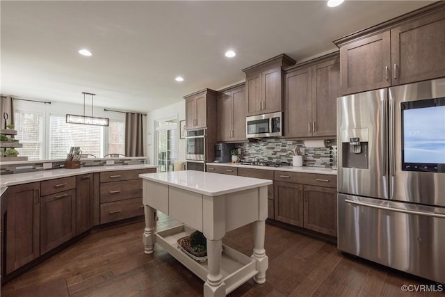 kitchen with pendant lighting, backsplash, dark hardwood / wood-style floors, and appliances with stainless steel finishes