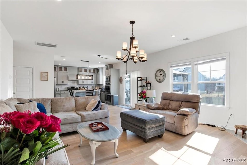 living room with an inviting chandelier and light wood-type flooring