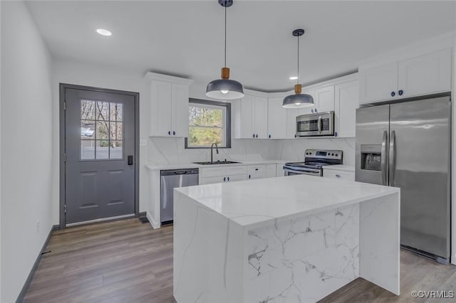 kitchen with a kitchen island, stainless steel appliances, decorative light fixtures, and white cabinetry