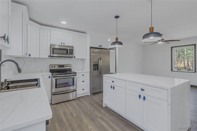 kitchen with appliances with stainless steel finishes, ceiling fan, decorative backsplash, white cabinets, and sink