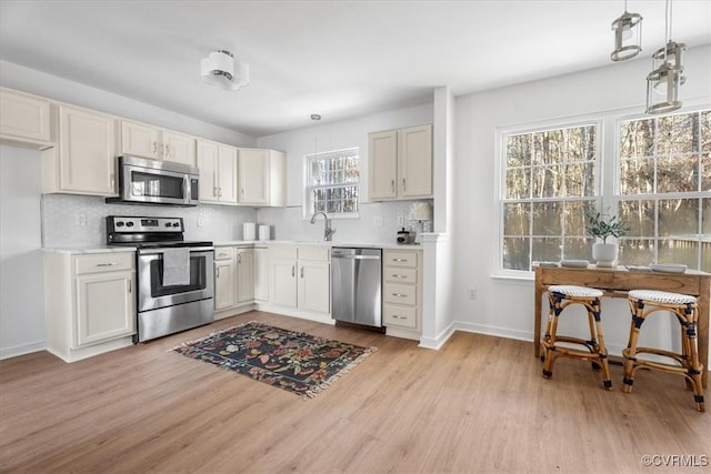 kitchen with stainless steel appliances, white cabinets, decorative light fixtures, and a wealth of natural light