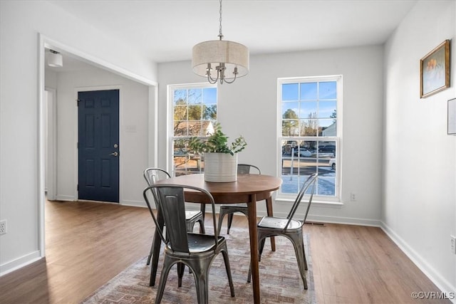 dining space with a healthy amount of sunlight, an inviting chandelier, and hardwood / wood-style flooring