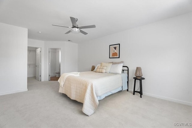 bedroom featuring light colored carpet, ceiling fan, a spacious closet, and a closet