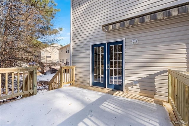 snow covered deck featuring french doors and a patio area