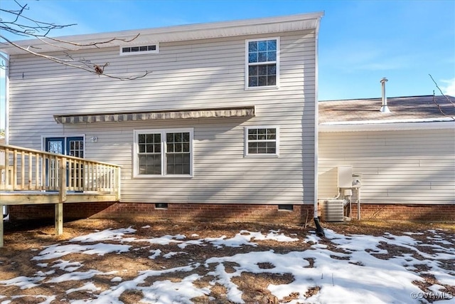 snow covered rear of property featuring central AC and a wooden deck